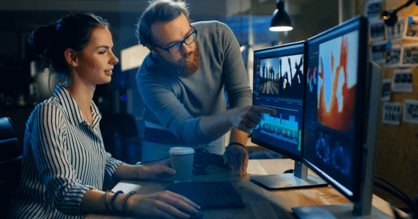 Two video editors reviewing footage together on a pair of monitors
